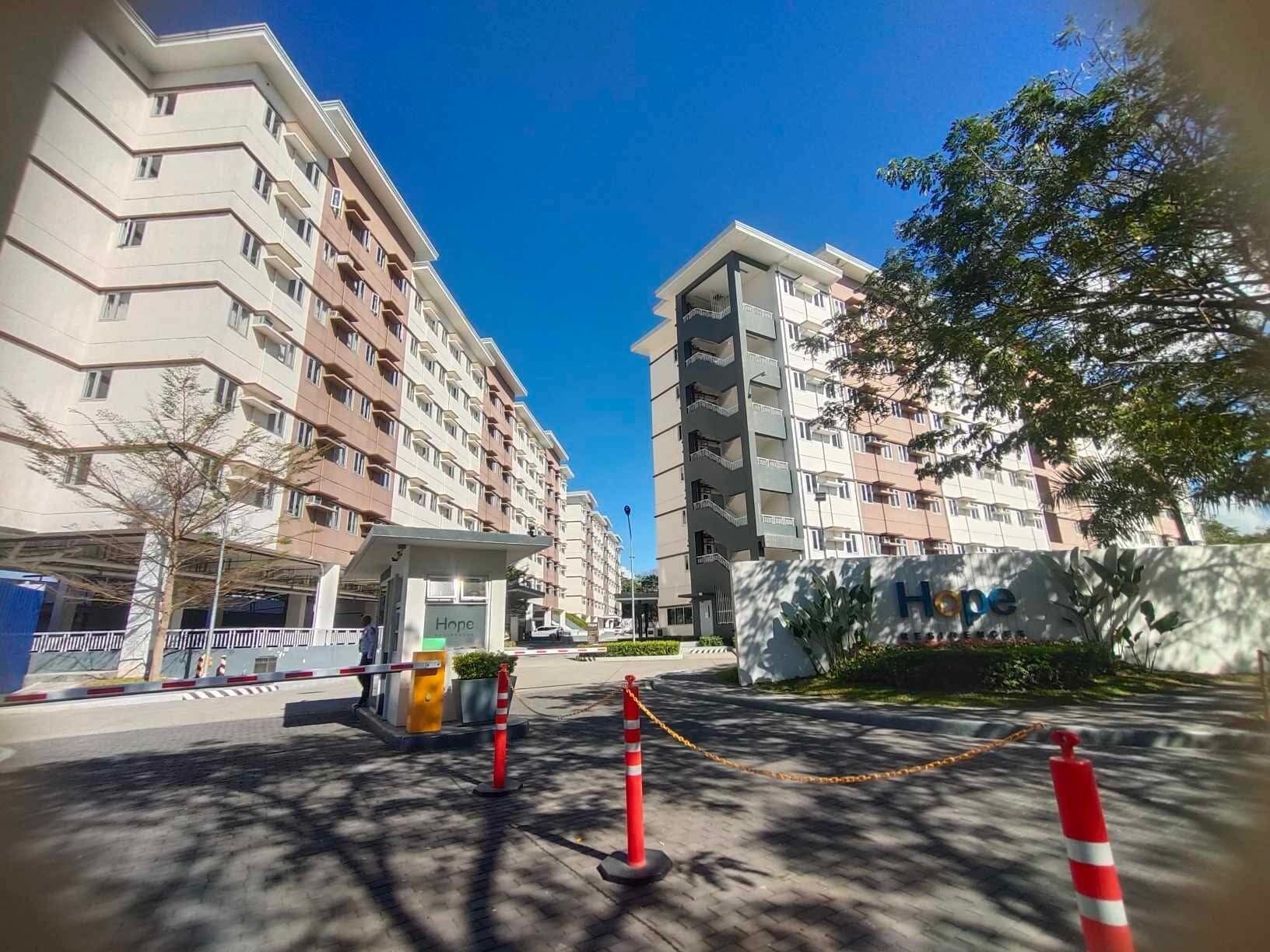 A multi-story hotel with a covered entrance, a parking area, and a gated driveway.