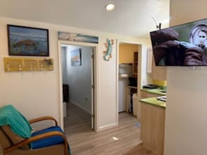 Una habitación con cama, televisión, escritorio y puerta que da a otra estancia.