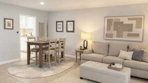 Ein Wohnzimmer mit einer Couch, einem Hocker und einem Essbereich mit Stühlen und einem Tisch.