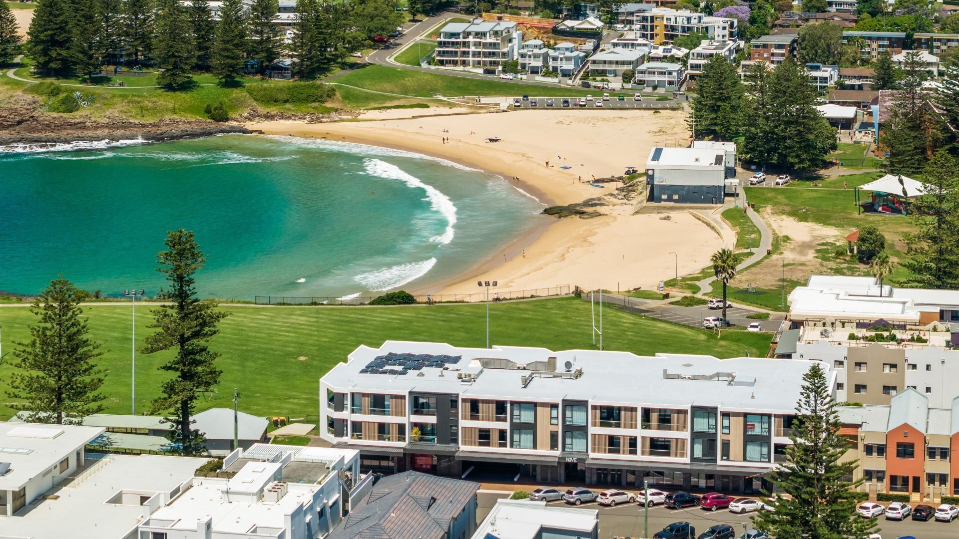 A coastal hotel with a beach view, modern architecture, and a parking area.