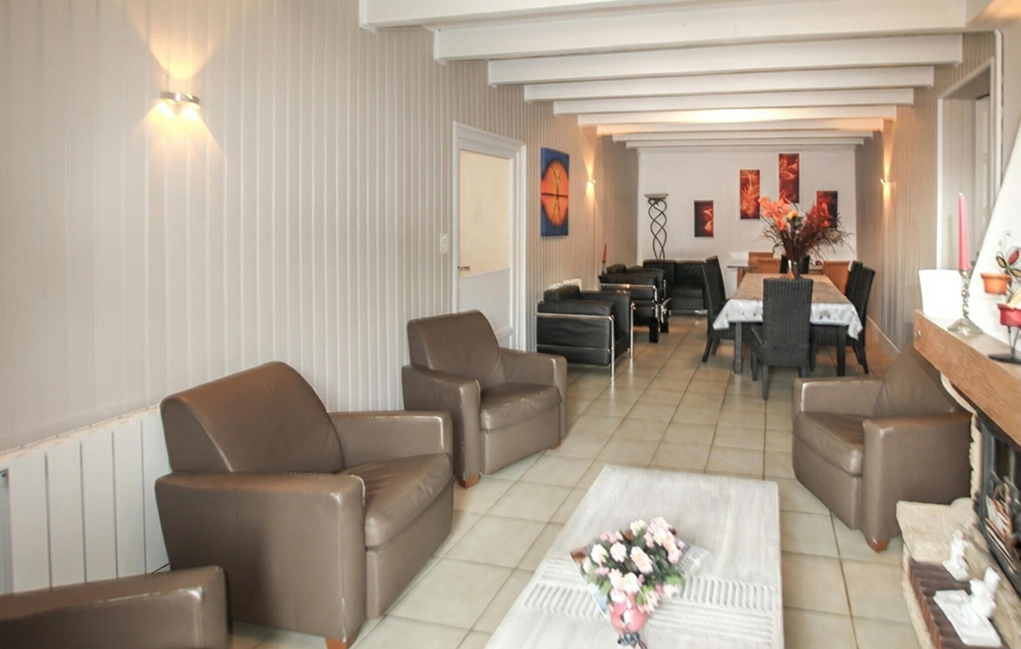 A modern living room with leather sofas, a dining table, and a coffee table with flowers.