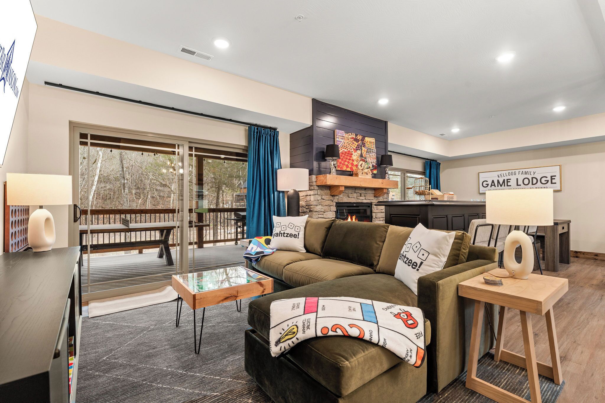 A modern living room with a sofa, coffee table, and a fireplace. There is a sign on the wall that reads 'Kellogg Family Game Lodge.'