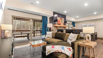 A modern living room with a sofa, coffee table, and a fireplace. There is a sign on the wall that reads 'Kellogg Family Game Lodge.'