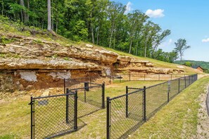 Un'area esterna recintata con una scogliera rocciosa e un edificio sullo sfondo.