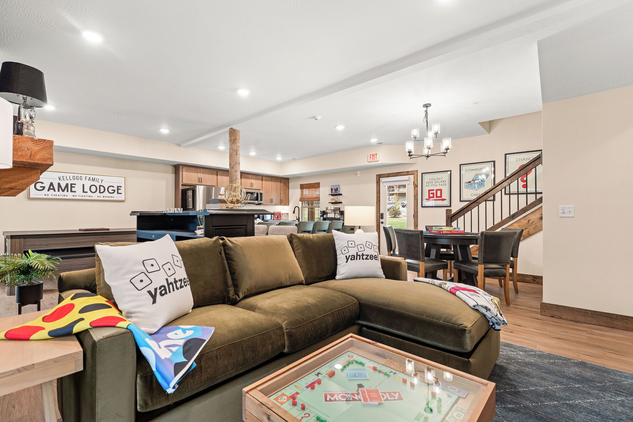 A modern living room with a sectional sofa, a coffee table with board games, and a kitchen in the background.