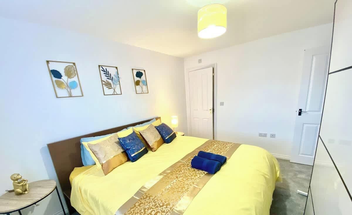 Ein Schlafzimmer mit einem Bett, Kissen, einem Nachttisch und Wandbildern.