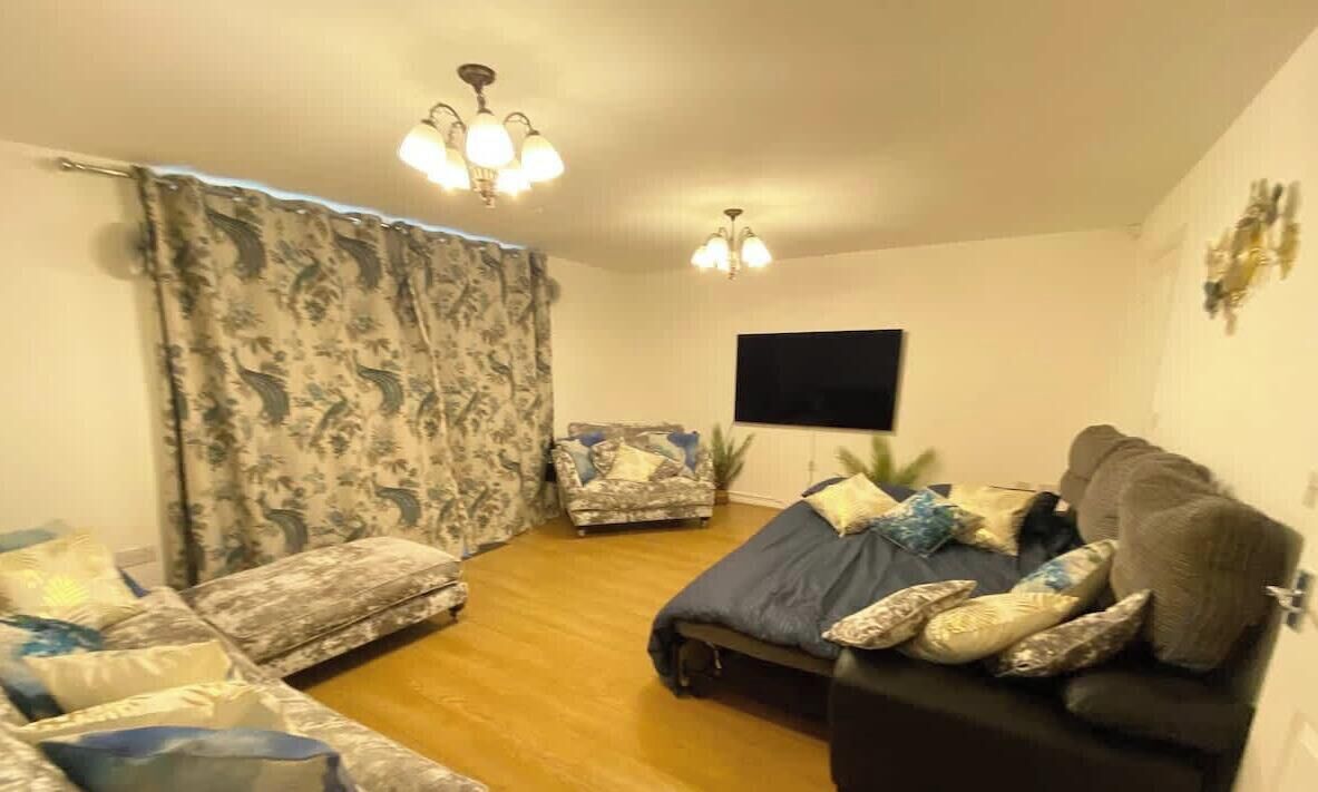 A living room with a sofa, a chair, a TV, and a ceiling light fixture.