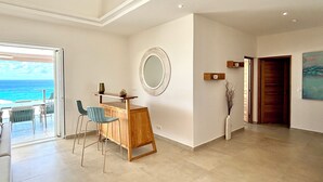 A spacious room with a wooden desk, two chairs, a round mirror, and a view of the ocean through a sliding door. - Villa Top of the Rock 2 (Saint-François)