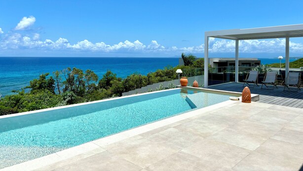 A pool with a clear view of the ocean, a covered patio area, and a modern architectural style. - Villa Top of the Rock 2 (Saint-François)