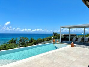 Piscina com vista clara do oceano, área de varanda coberta e estilo arquitetônico moderno.