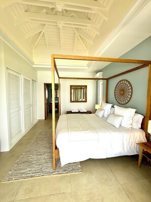 A bedroom with a four-poster bed, a large mirror, and a decorative wall piece. - Villa Top of the Rock 2 (Saint-François)