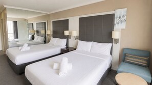 Une chambre d’hôtel avec deux lits, un miroir, une chaise et une table ronde.
