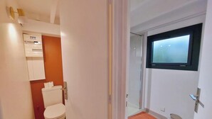 Un baño con inodoro, un armario y una ventana.