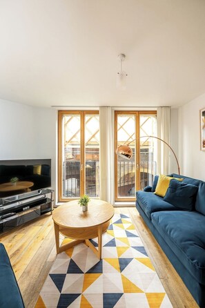 Ein modernes Wohnzimmer mit Fernseher, Sofa und Couchtisch.