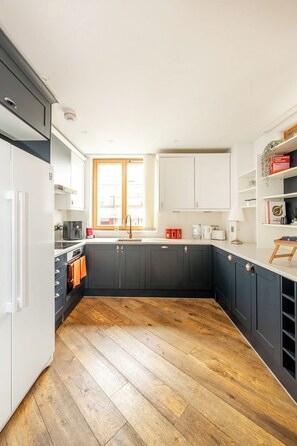 Eine moderne Küche mit dunklen Schränken, Holzboden und einem Fenster mit Blick.