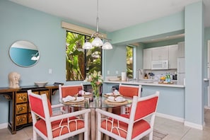 A dining area with a round table, white chairs, and a hanging light fixture. - 3 Grand Champions | Treeline View | Sleeps 14 | Free Car w/ 6+ Nts | ML-3786 (Wailea)