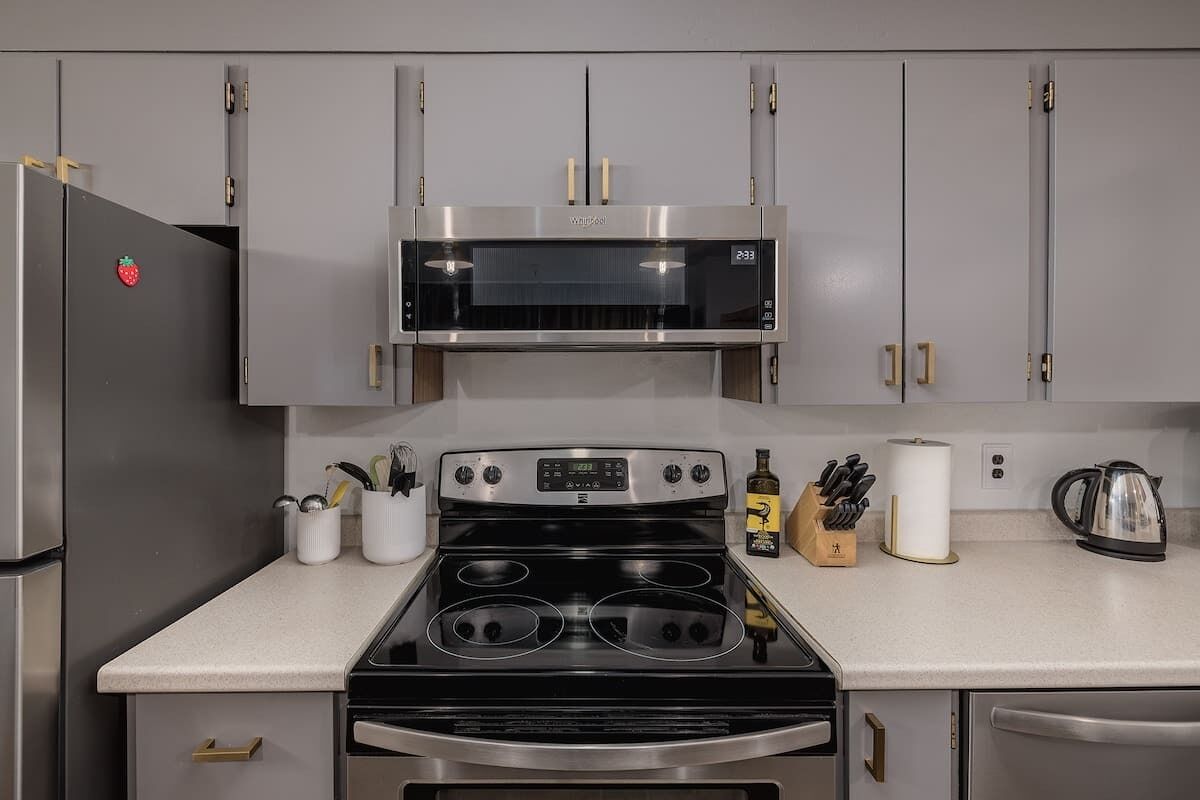 A kitchen with a stainless steel refrigerator, a microwave, an oven, and a stovetop. There are cabinets above the countertop, and a coffee maker is visible on the right.