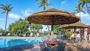 A pool area with a stone floor, lounge chairs, and thatched umbrellas. - Kaanapali Royal | Ocean View 4 BR, Sleeps 11 | Car Incl. w/ 6+ Nights | KRO ML-3794 by KBM (Lahaina)