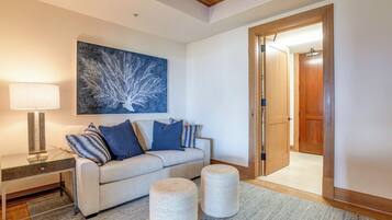 A living room with a sofa, a lamp, a painting, and a door leading to another room.
