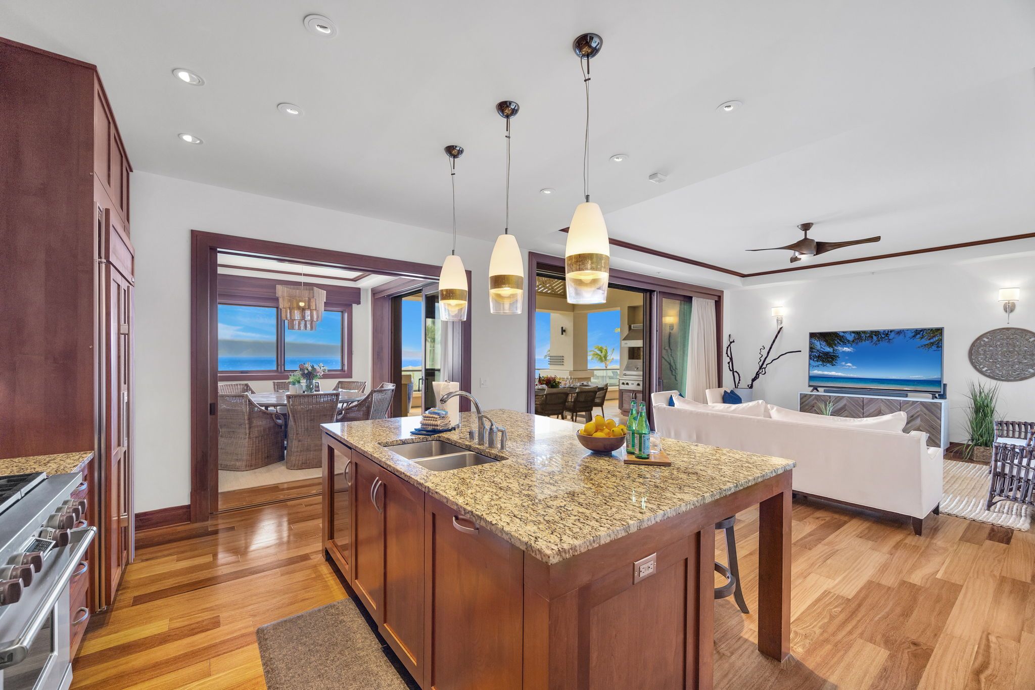 A modern kitchen with granite countertops, a central island, and pendant lighting.
