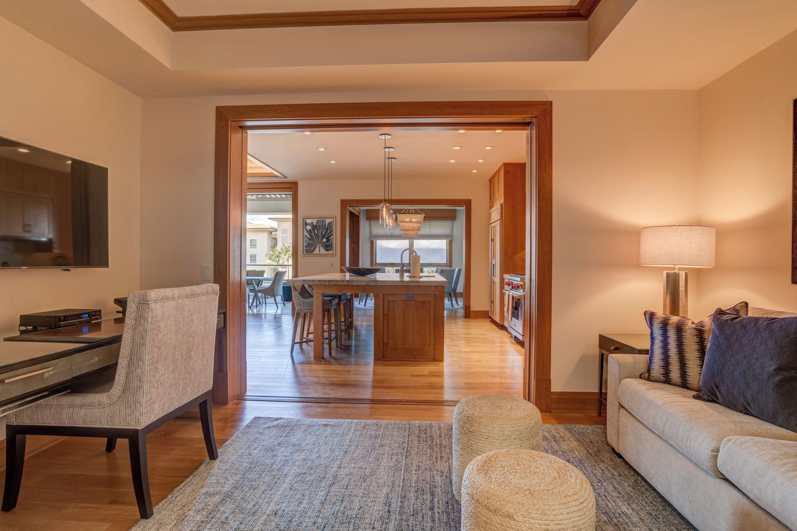 A modern living room with a TV, a sofa, a coffee table, and a dining area with a kitchen in the background.