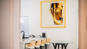 Een moderne keuken met een marmeren aanrecht, barstoelen, een ronde tafel en een kunstwerk in een lijst aan de muur.