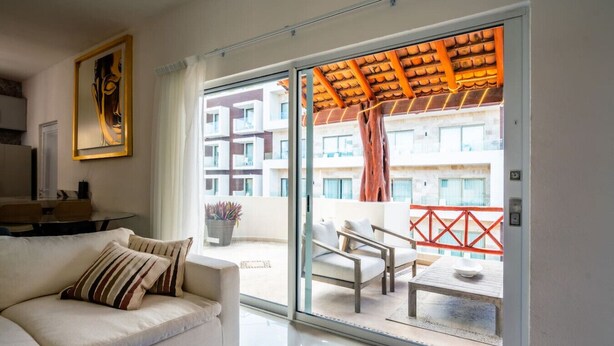Een moderne woonkamer met een bank, een eettafel en een balkon met uitzicht op het gebouw.