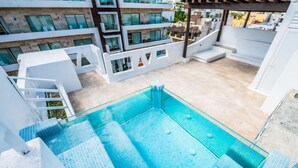 Een zwembad op het dak met helderblauw water, omgeven door witte balkons en een moderne architectuur.