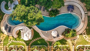 Luchtbeeld van een resort met een groot zwembad, gebogen paden en weelderige beplanting.