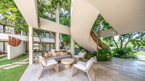 A modern outdoor seating area with a sofa, chairs, and a round table. - Peaceful Studio Retreat with Hot Tub & King Bed (Tulum)