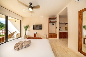 Ein modernes Hotelzimmer mit einem großen Bett, einem Deckenventilator, einem Fernseher, einer Topfpflanze und Blick ins Freie.