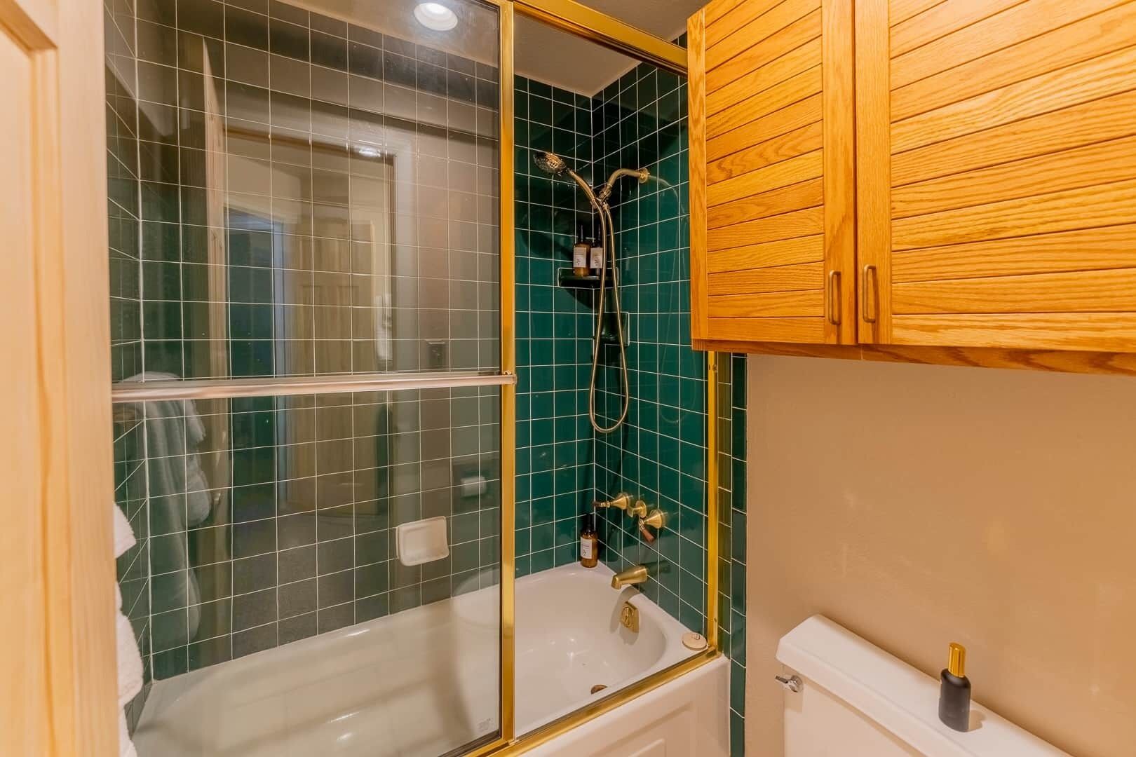 A bathroom with a bathtub, a shower, and wooden cabinets.