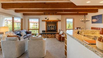 A spacious living area with a fireplace, a kitchen with a granite countertop, and a large window offering a view of the outside.