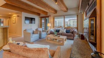 A spacious living area with a fireplace, a sofa set, a coffee table, and large windows offering a view of the city.