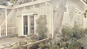 A house with a stone foundation, a porch with a railing, a door, and a window.