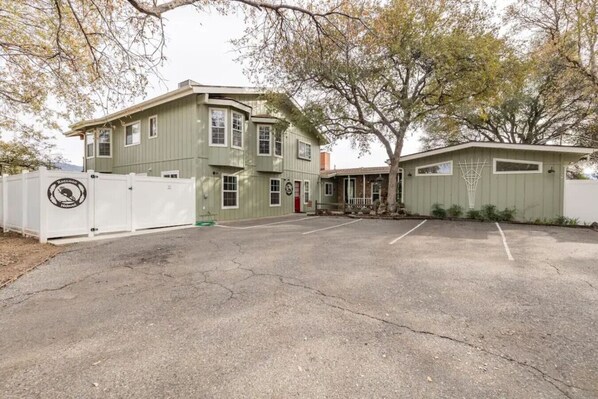 A two-story building with a garage, a fenced driveway, and a basketball hoop.