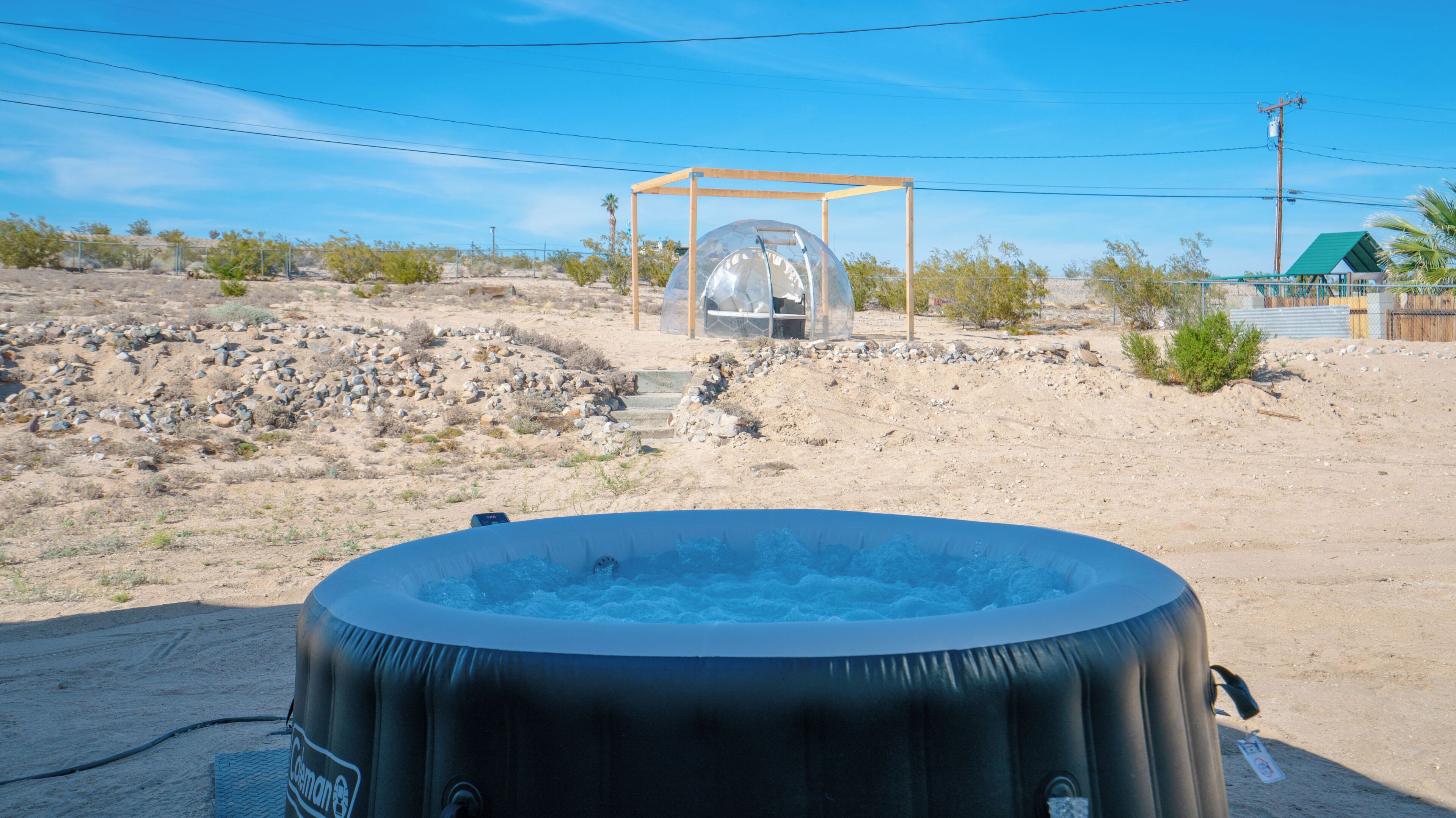 Een jacuzzi in een woestijnlandschap, met een transparante koepelstructuur op de achtergrond.