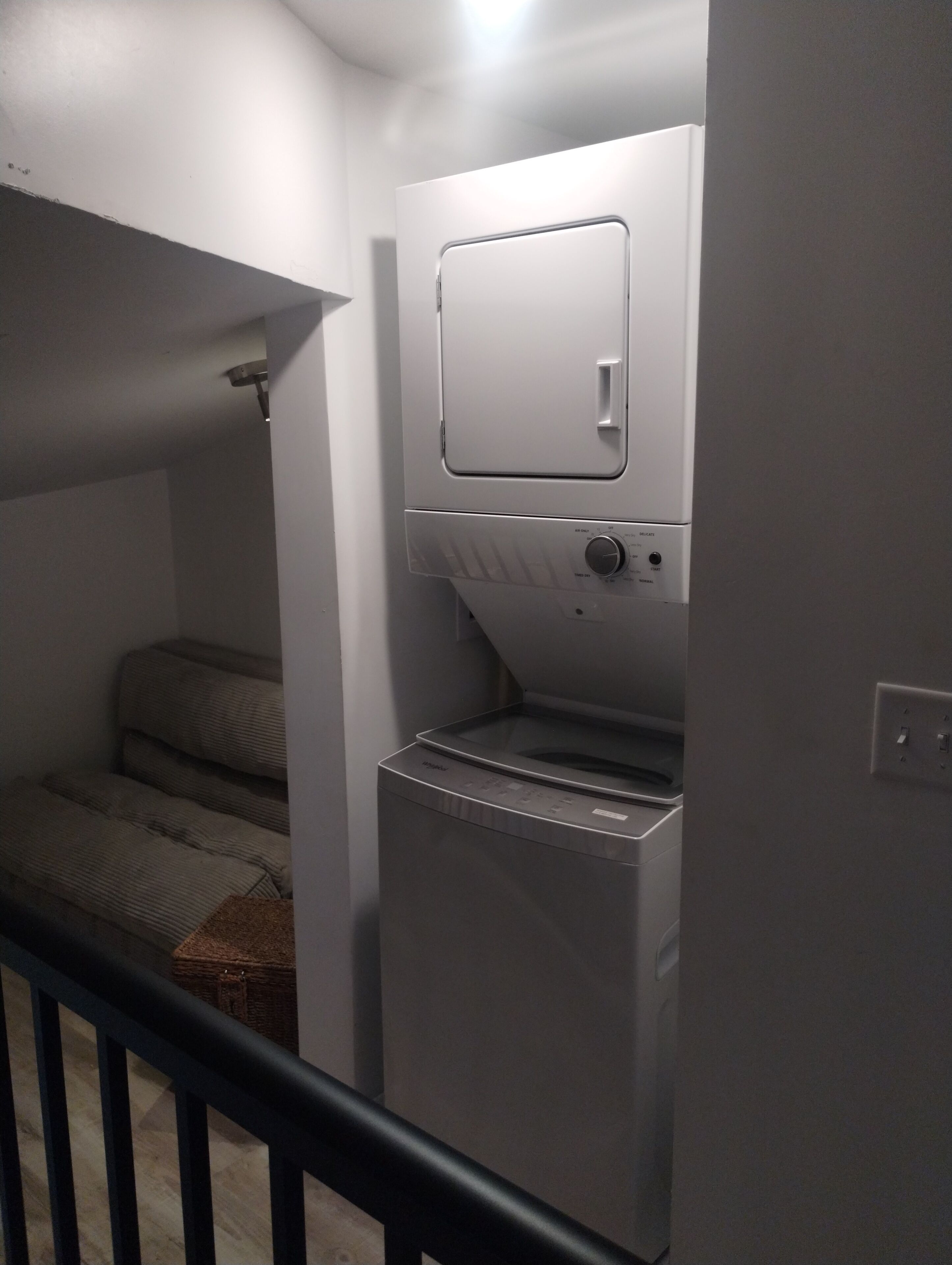 Habitació senzilla amb llit, rentadora i un petit armari.
