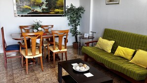 Una habitación con una mesa de comedor, sillas, un sofá, una mesa baja y un cuadro en la pared.