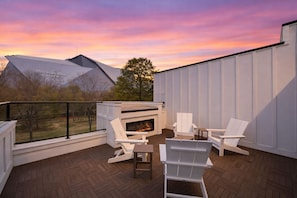 Eine Terrass mit Kamin, weißen Adirondack-Stühlen und Blick auf einen Berg.