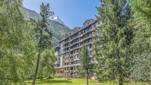 A multi-story hotel with balconies, surrounded by trees and mountains. - Cosy Mont-Blanc – Centre Chamonix - Welkeys (Chamonix-Mont-Blanc)