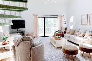 A modern living room with a sofa, coffee table, ottoman, and a television. - 5 minutes to Cherry Grove! Stay in style and comfort at the beach! (Little River)