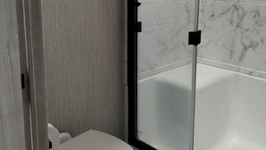 Ein Badezimmer mit Toilette, Duschkabine und Badewanne.