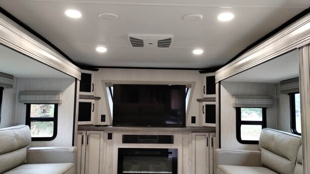 Ein geräumiges Wohnmobil-Interieur mit einem großen Flachbildfernseher, einem Kamin und gemütlichen Sitzbereichen.