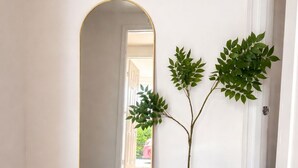 A hallway with a large mirror, a potted plant, and a rug on the floor. - Ariia Fort Lauderdale Airport (Fort Lauderdale)