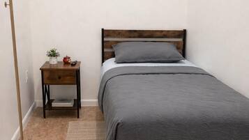 Une chambre à coucher comprenant un lit, une table de chevet, une lampe sur pied et deux œuvres d’art encadrées accrochées au mur.