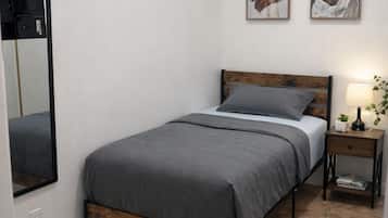 A bedroom with a bed, a nightstand, a lamp, a mirror, and two framed pictures on the wall.