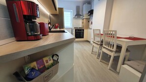 A compact kitchen with a coffee maker, a small oven, and a dining area with a table and chairs. - Sunny and Cozy Apartment (Brașov)
