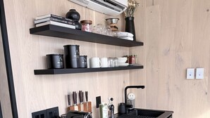 Et moderne køkken med en sort bordplade, indbyggede hylder, en kaffemaskine og en aircondition-enhed.