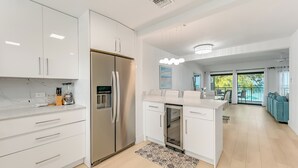 Una cucina moderna con mobili bianchi, un frigorifero integrato e un'area pranzo con vista.